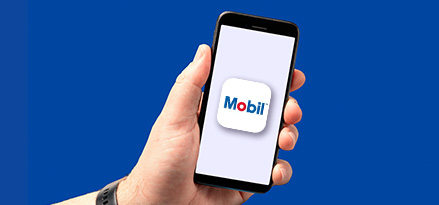 A customer holding a phone showing the Mobil NZ App.