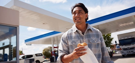 Man walks to his car enjoying a Mobil pie.